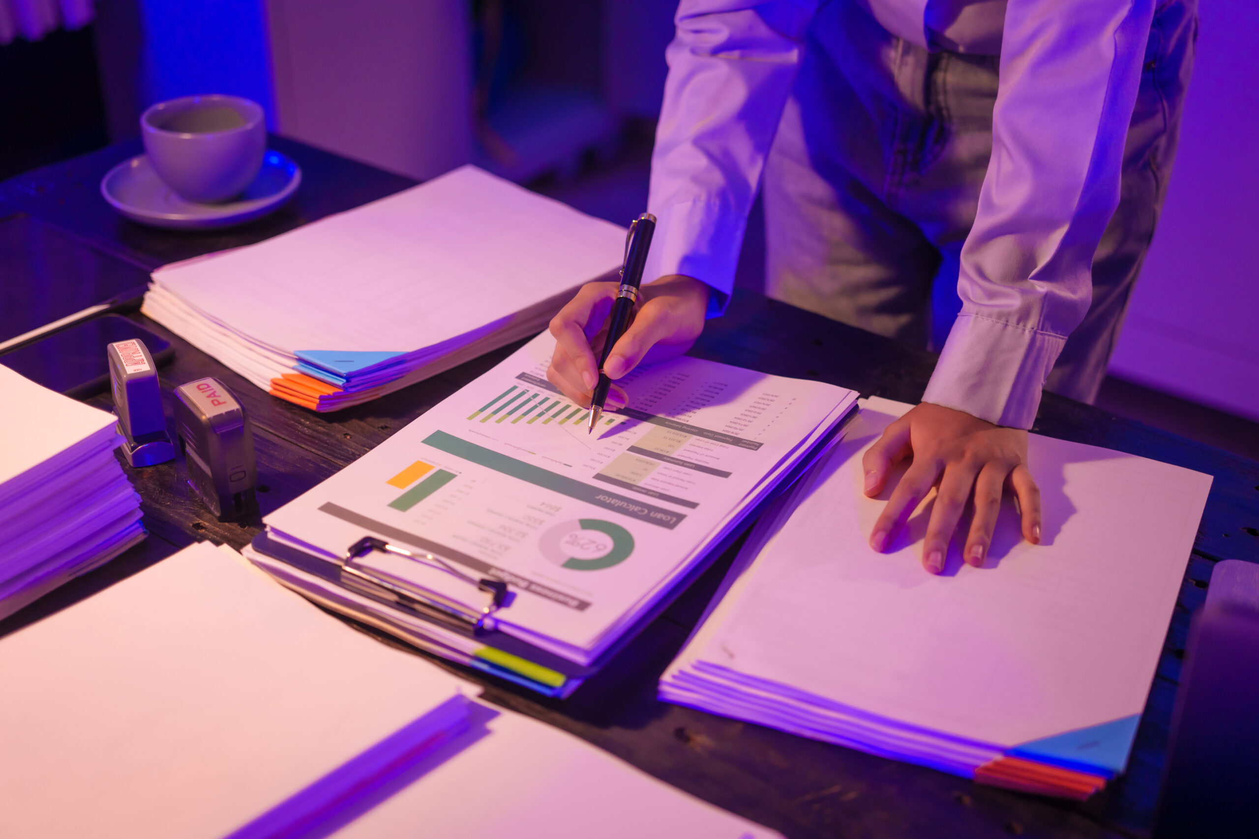 young Asian business trainee works late into night at her desk,