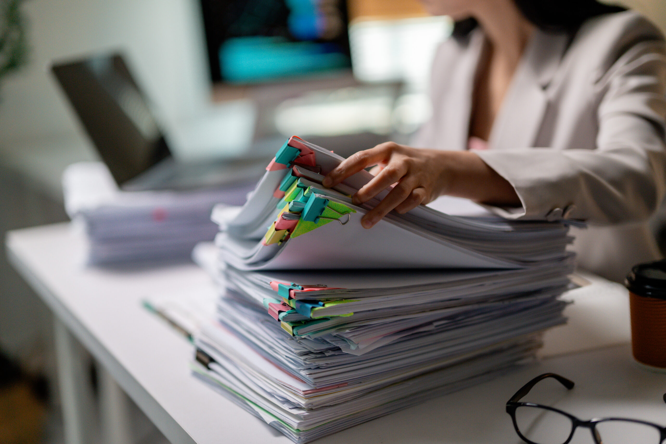 Office worker looking for specific document in large stack of paperwork